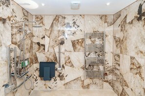 Une salle de bain avec une douche, un porte-serviettes et un mur en marbre.