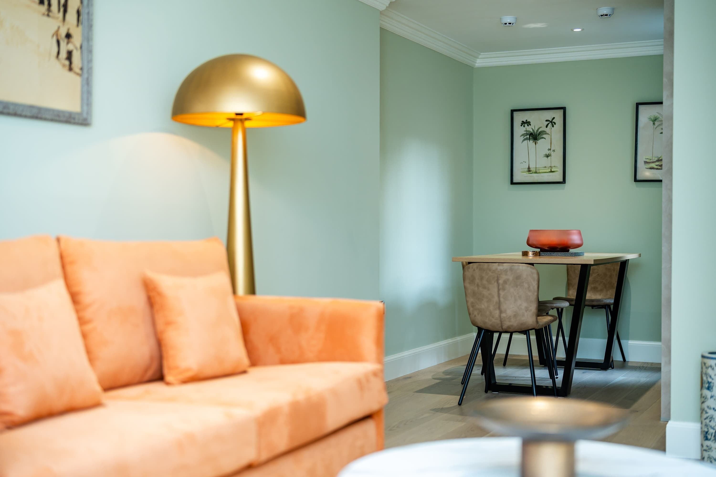 Ein Wohnzimmer mit einer Couch, einer Stehlampe und einem Essbereich mit Tisch und Stühlen.