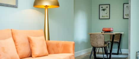 Una sala de estar con un sofá, una lámpara de pie y una zona comedor con una mesa y sillas.