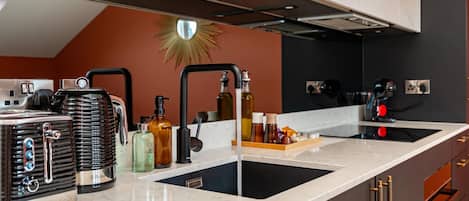 A modern kitchen with a marble countertop, stainless steel appliances, and a backsplash with a sunburst design.