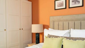A hotel room with a bed, a nightstand, a lamp, and a wardrobe. - Dragon Suites 1 Bed Luxury Apartment (Edinburgh)