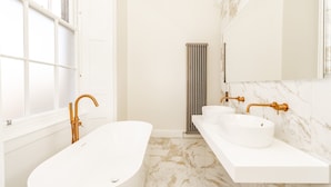 A modern bathroom with a freestanding bathtub, a double sink vanity, and a large mirror. - Swinton Suite - 1 Bed Luxury Apartment (Edinburgh)
