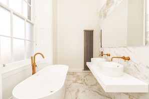 Ein modernes Badezimmer mit freistehender Badewanne, einem Doppelwaschtisch und einem großen Spiegel.
