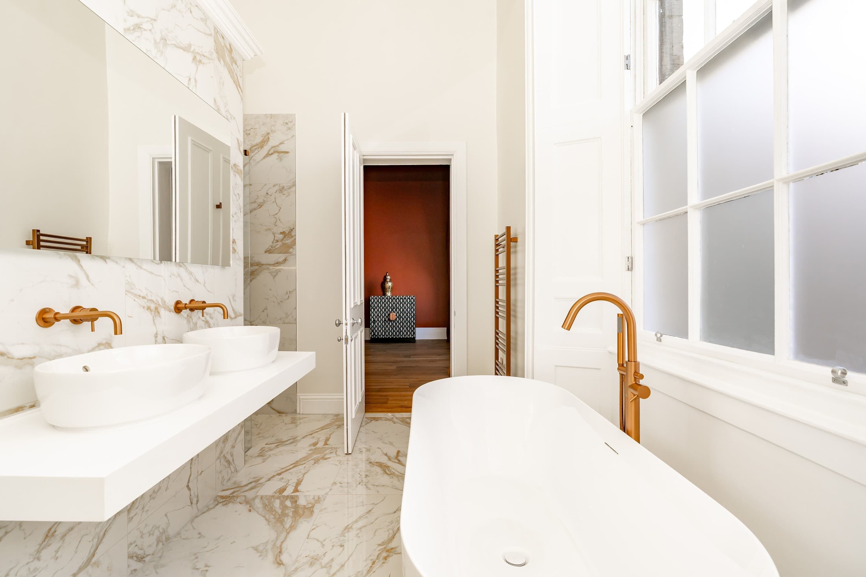 A modern bathroom with two sinks, a freestanding bathtub, and a large mirror.