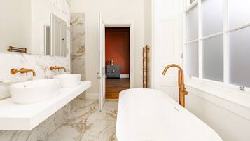 A modern bathroom with two sinks, a freestanding bathtub, and a large mirror.
