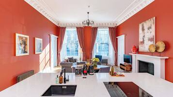 A spacious living area with a large island, a fireplace, and a view of the city through large windows.