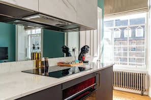Une cuisine moderne dotée d’une grande fenêtre, d’une cuisinière intégrée et d’un miroir au-dessus du plan de travail.