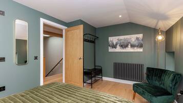 A bedroom with a bed, a chair, a radiator, a door, and a wall-mounted artwork.