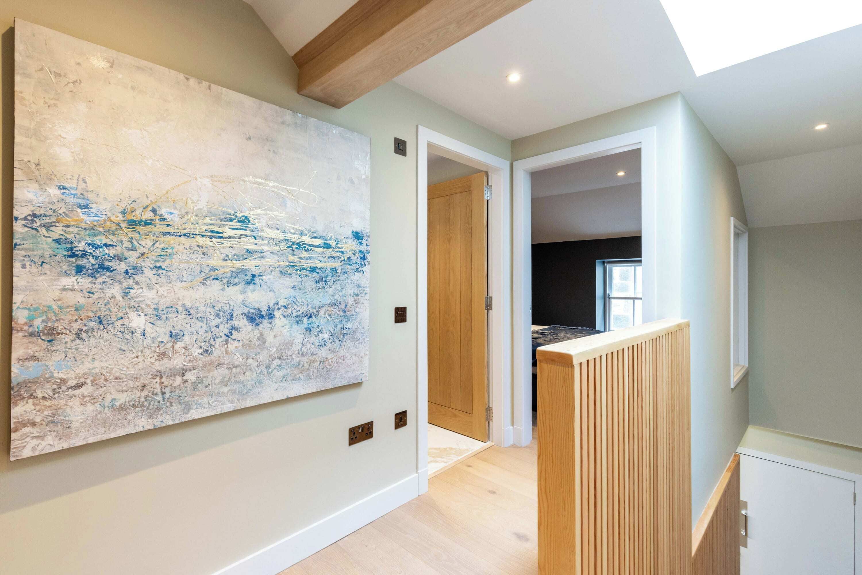 A hallway with a large abstract painting, wooden doors, and a view into another room.