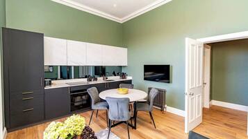 A modern kitchen with dark cabinetry, a white countertop, and a dining area with a round table and chairs.