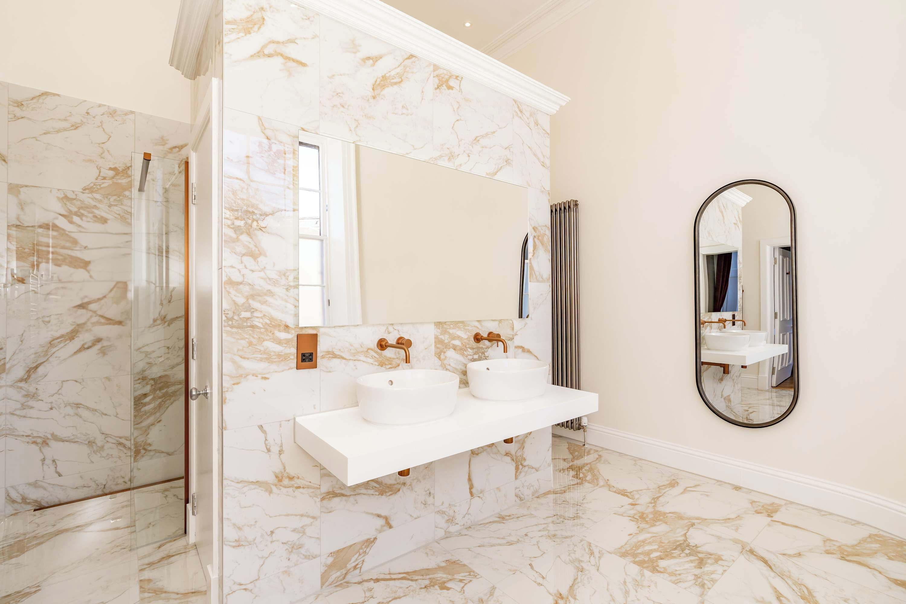 A bathroom with marble walls, a white sink, and a large mirror.