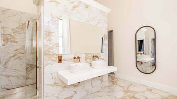 A bathroom with marble walls, a white sink, and a large mirror.