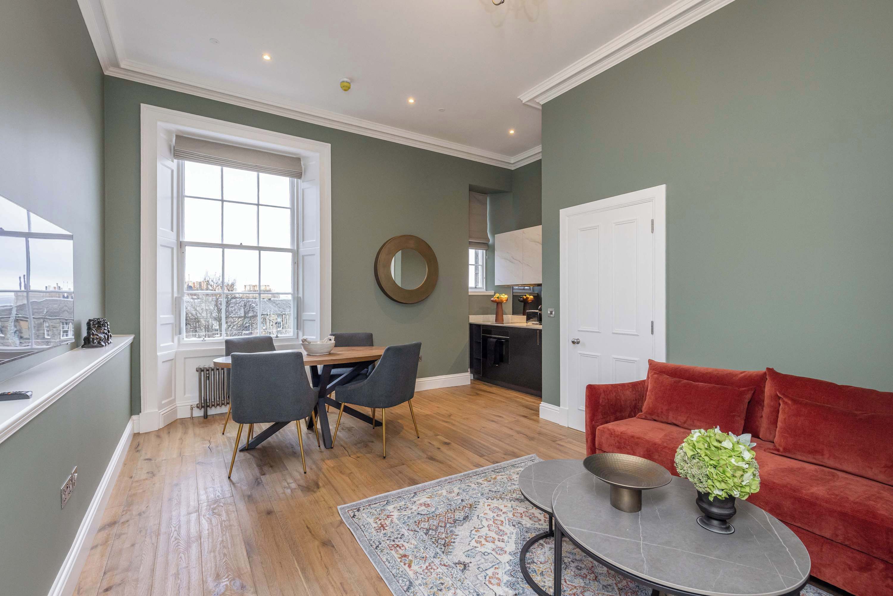 A modern living room with a dining area, a kitchen, and a red sofa.