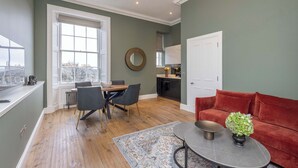 Una sala de estar moderna con comedor, cocina y un sofá rojo.