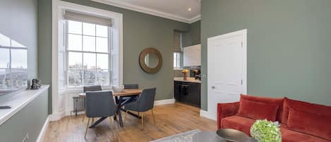 A modern living room with a dining area, a kitchen, and a red sofa.