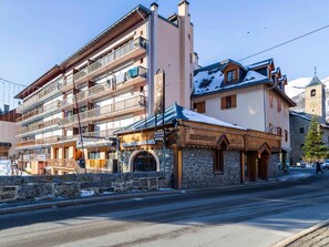 A multi-story building with balconies, a restaurant, and a mountain view. - Studio for 4 in Valloire, east-facing (Valloire)