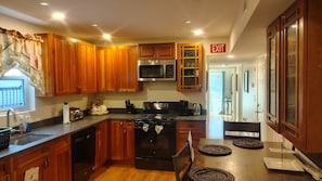A kitchen with wooden cabinets, a stainless steel microwave, a black stove, and a sink.