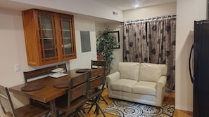 A dining area with a wooden table and chairs, a beige sofa, and a patterned rug.