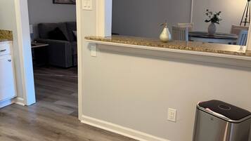 A kitchen with a granite countertop, a ceiling fan, and a trash can.