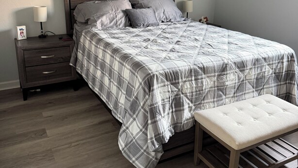 A bedroom with a bed, nightstands, a bench, a ceiling fan, and artwork on the walls. - Perfect Location for Gameday (Oxford)