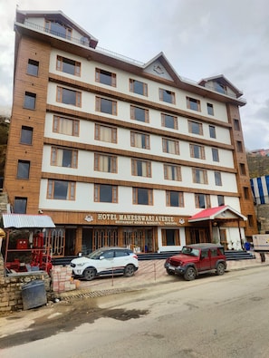 A multi-story hotel with a sign for 'Hotel Maheshwari Avenue' indicating it offers restaurant rooms and banquets.