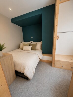 A bedroom with a bed, a wooden bench, a potted plant, and a ceiling light. - Apartment Sleeps 4 - Town Centre & Near Beach (Newquay)