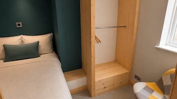 Une chambre à coucher avec un lit, une armoire en bois, une chaise et une fenêtre.