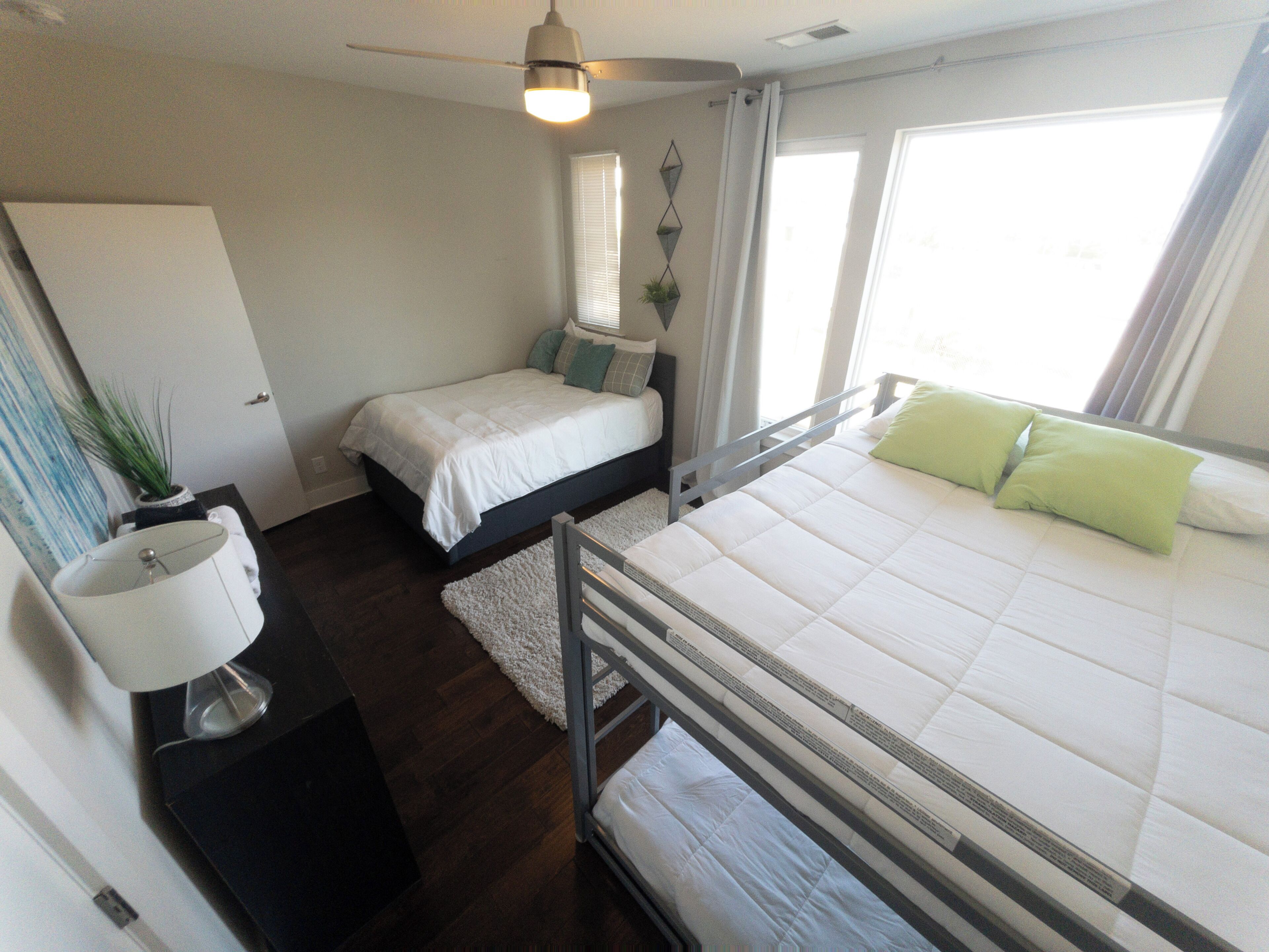 A bedroom with a bed, bedside tables, a ceiling fan, and a window.