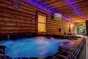 A wooden cabin interior with a hot tub, wooden walls, and a sign indicating a beer sign. - Amish-Built 5BR Cabin in Sky Harbor | Sleeps 12 | Game Room, Hot Tub (Sevierville)