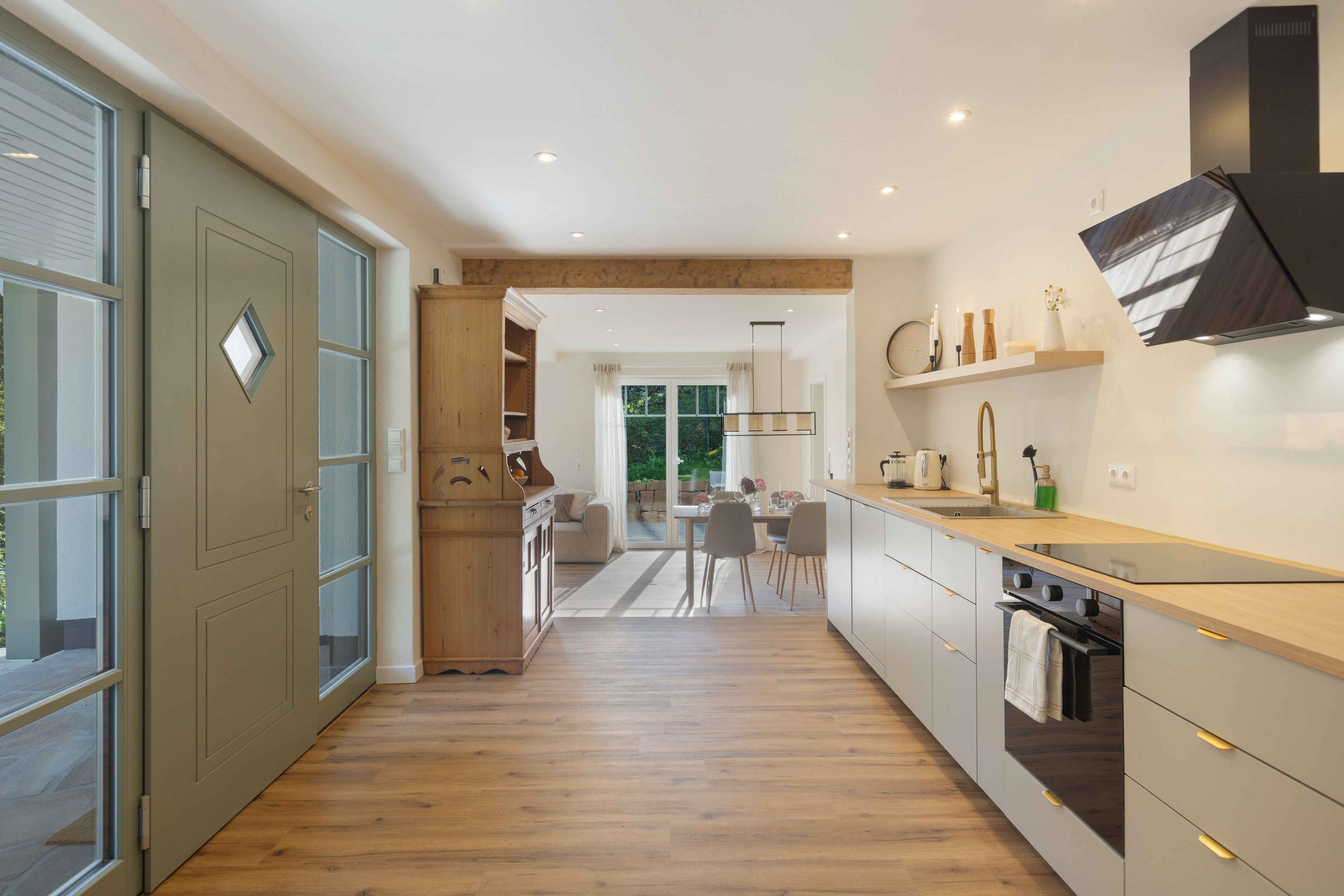 A modern kitchen with a wooden floor, a built-in oven, and a sink.
