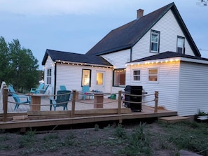 Een tweelaags huis met een terras, buitenmeubels en een barbecue.