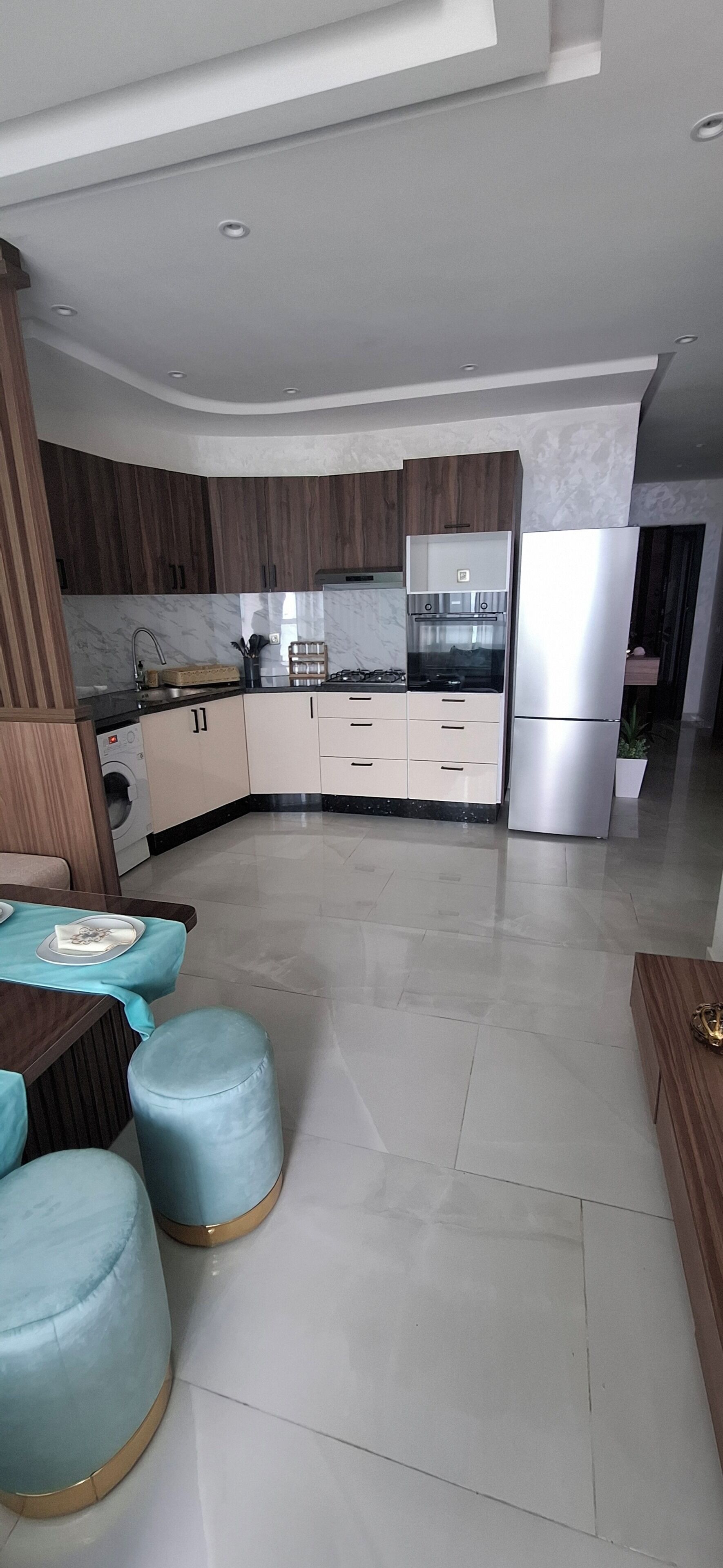 Eine moderne Küche mit Einbauofen, Edelstahlkühlschrank und Holzschränken.