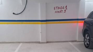 Eine überdachte Parkgarage mit weißem Boden, einem blauen und gelben Streifen und einem Schild mit der Aufschrift 'Stage 1 Apartment 2'.