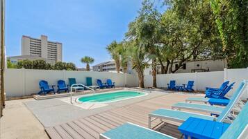 A pool area with blue lounge chairs and a small pool.