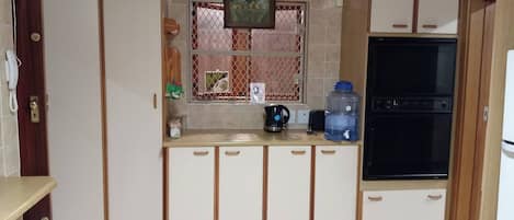 A kitchen with white cabinets, a black oven, and a water dispenser.