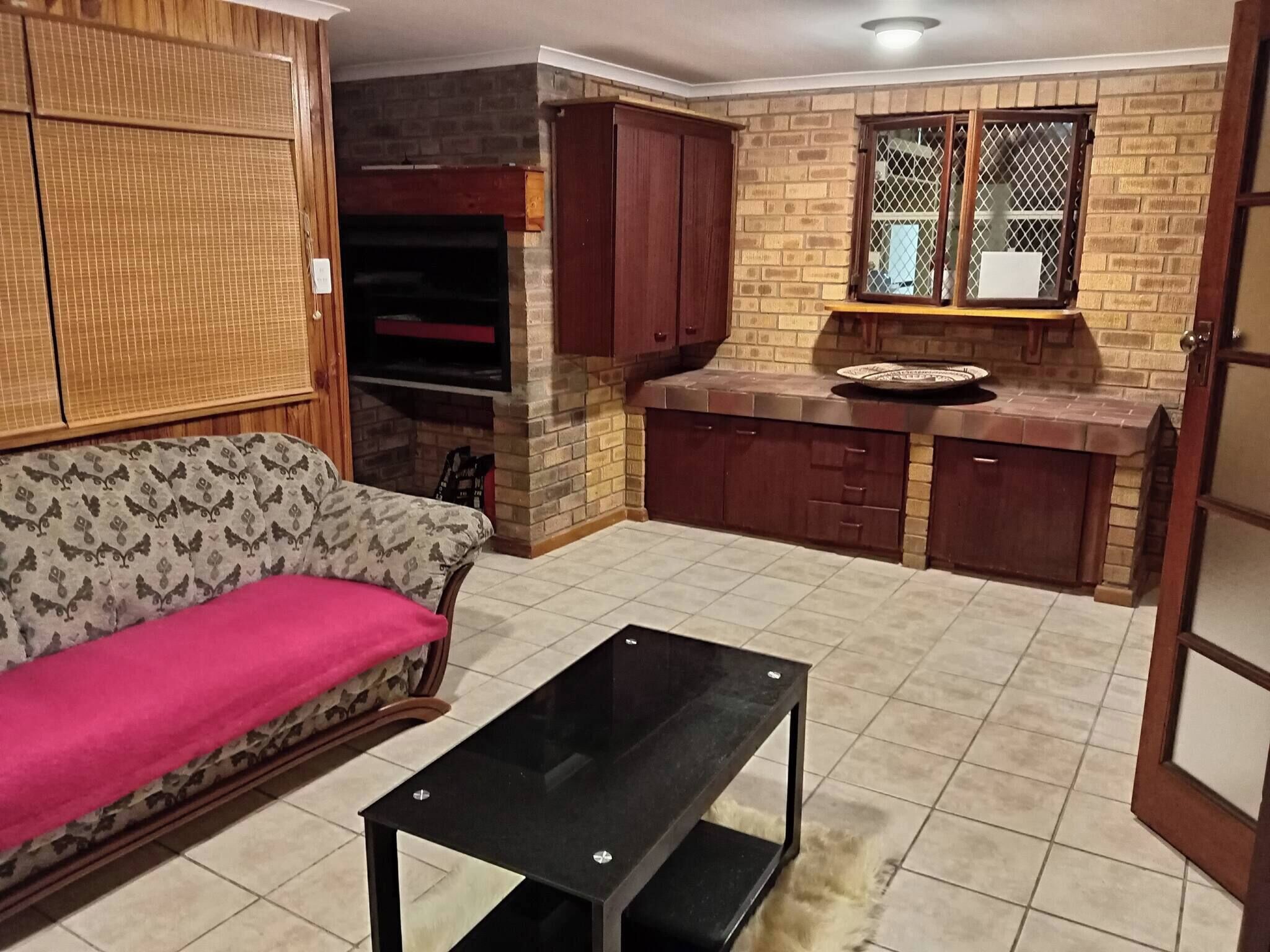 Ein kompakter Wohnbereich mit Sofa, kleinem Tisch, Küchenzeile mit Schränken und einem Kamin.