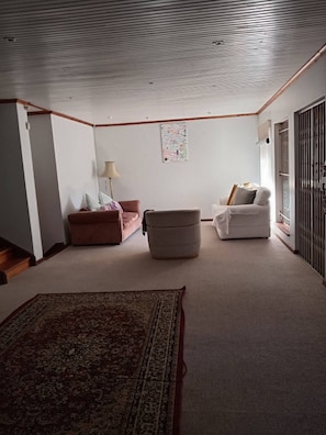 A living room with a sofa, ottoman, and a patterned rug. - The Victorian Villa House (Great Kei)