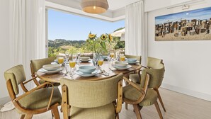Comedor con una mesa dispuesta para seis personas, sillas, lámpara colgante y vistas al exterior.