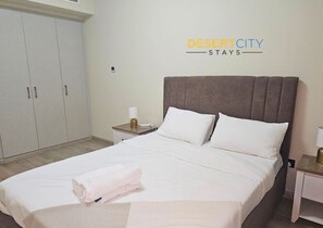 Habitación de hotel con cama, mesita de noche, armario y un cartel que dice 'DESERTCITY STAYS'.