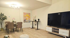 A modern living room with a dining area, a flat-screen TV, and a painting on the wall. - Sea View | Duplex Unit | Al Marjan Island | RAK (Ras Al Khaimah)
