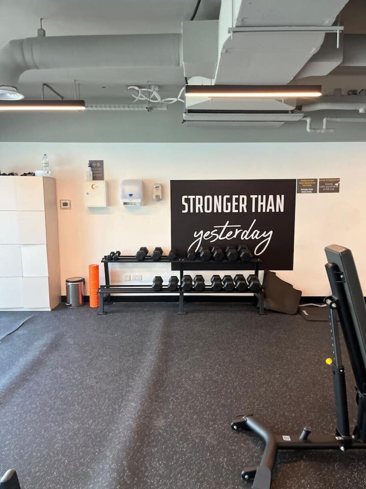 Ein Fitnessstudio mit motivierendem Spruch, Hanteln und Trainingsgeräten.