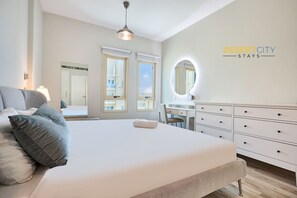 A modern bedroom with a large bed, a desk, and a dresser. - Elegant 1BR Apartment | Prime Greens Community (Dubai)