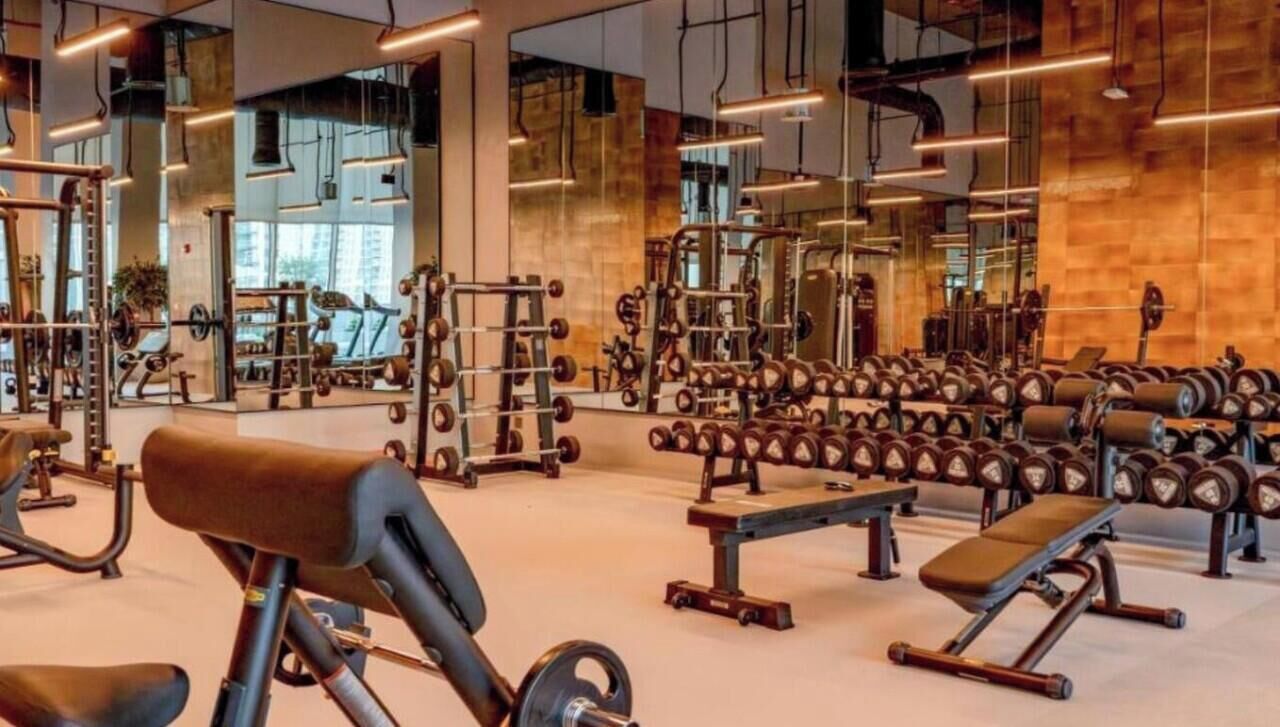 Une salle de sport équipée de divers appareils d’exercice, de miroirs et d’un mur en bois.