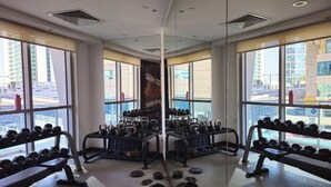 Ein Fitnessstudio mit Gewichthebern, großen Fenstern und Blick auf die Stadtlandschaft.