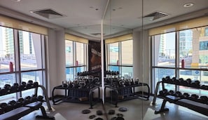 A gym with weightlifting equipment, large windows, and a view of the cityscape. - Close to Marina Promenade | Restaurant`s nearby (Dubai)