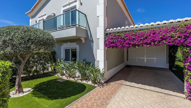A two-story building with a balcony, a garage, and a well-maintained garden. - Boavista - Golf View Villa (Lagos)