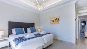 A modern hotel room with a large bed, a chandelier, a painting, and a TV. - Boavista - Golf View Villa (Lagos)