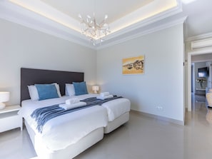 A modern hotel room with a large bed, a chandelier, a painting, and a TV. - Boavista - Golf View Villa (Lagos)