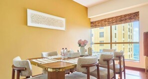 A hotel room with a large window, a dining table with chairs, a vase with flowers, and a framed artwork on the wall. - Close to JBR Beach | Ain Dubai view (Giant Wheel) (Dubai)