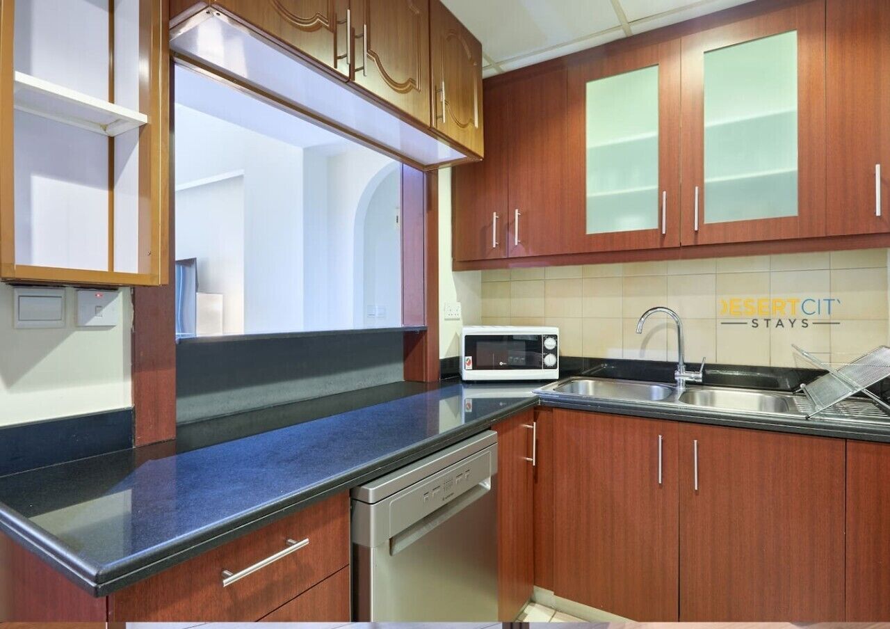A kitchen with wooden cabinets, a microwave, a dishwasher, and a sink.